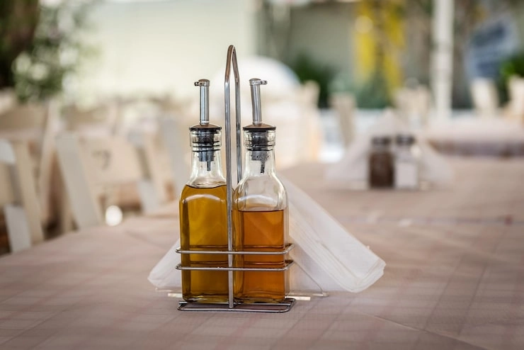 Two bottles of oil in a holder on a table