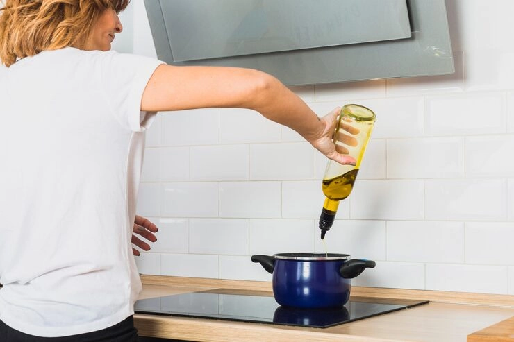 woman using oil bottle in kitchen